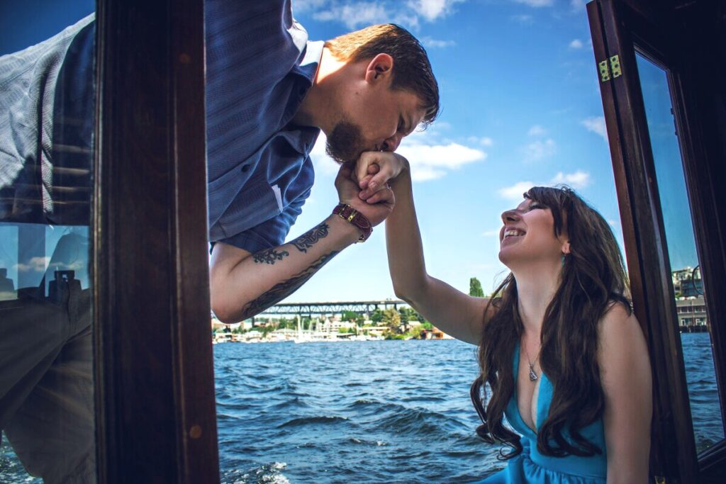 Elizabeth and Zack's original elopement on a boat on Lake Union in Seattle Zack Kissing Elizabeth's hand ofer the water ez elopements beginning