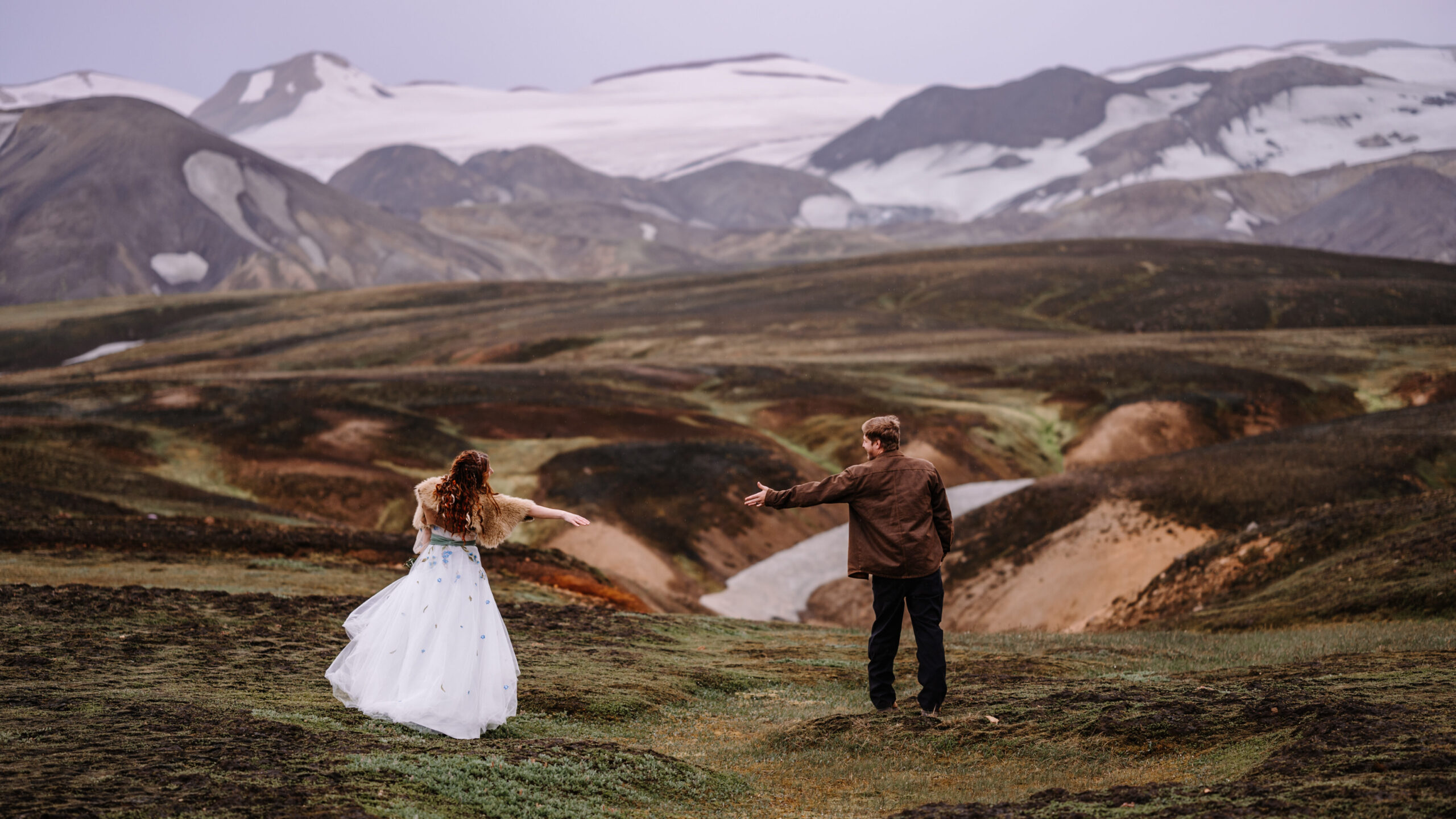 Couple exploring a picturesque spot in the colorful mountains of Iceland on their elopement day by EZ Elopements