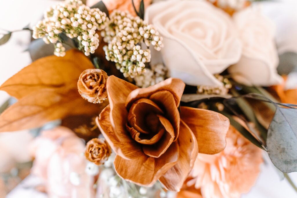 Overview of a sola wood bouquet made with orange, ivory, tan, white and natural wood flowers.