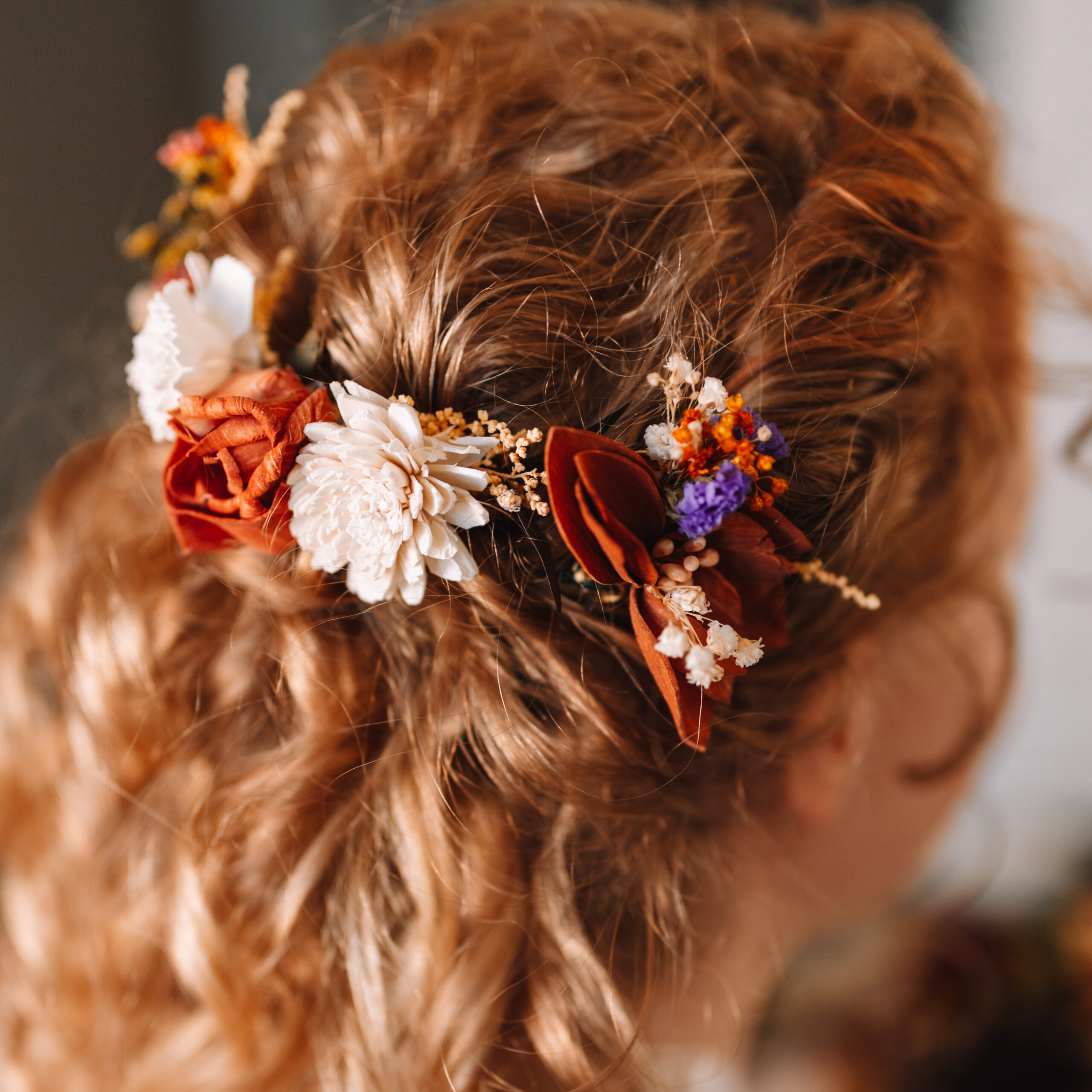 Bride with blonde curly hair with floral pins woven in. 